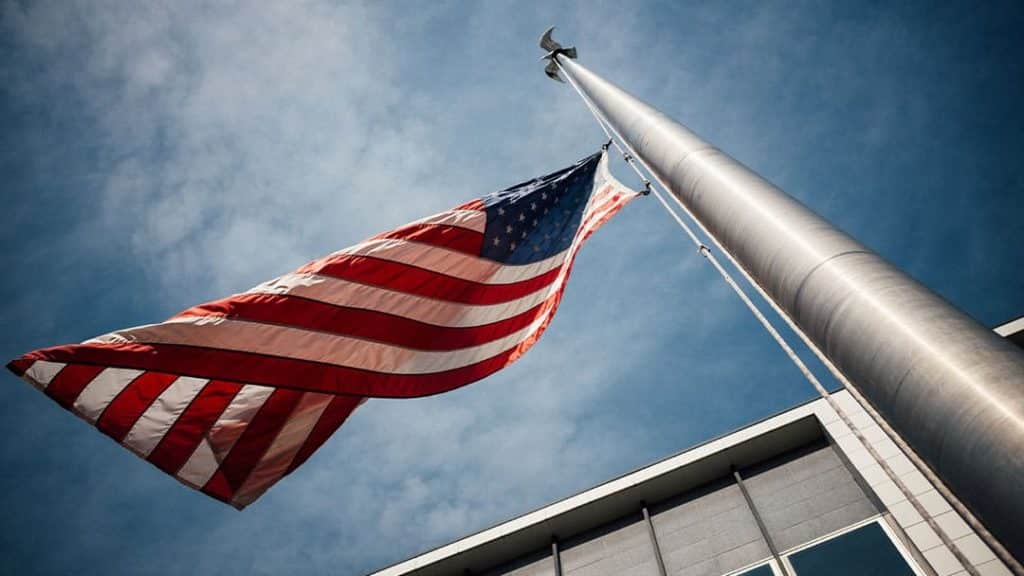 American flag hanging at government office photographed towards a blue sky blowing in wind