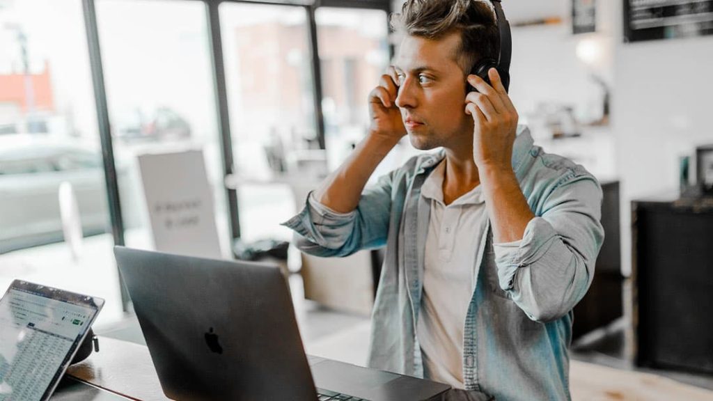 Male entrepreneur telemarketer sitting in office putting on headset